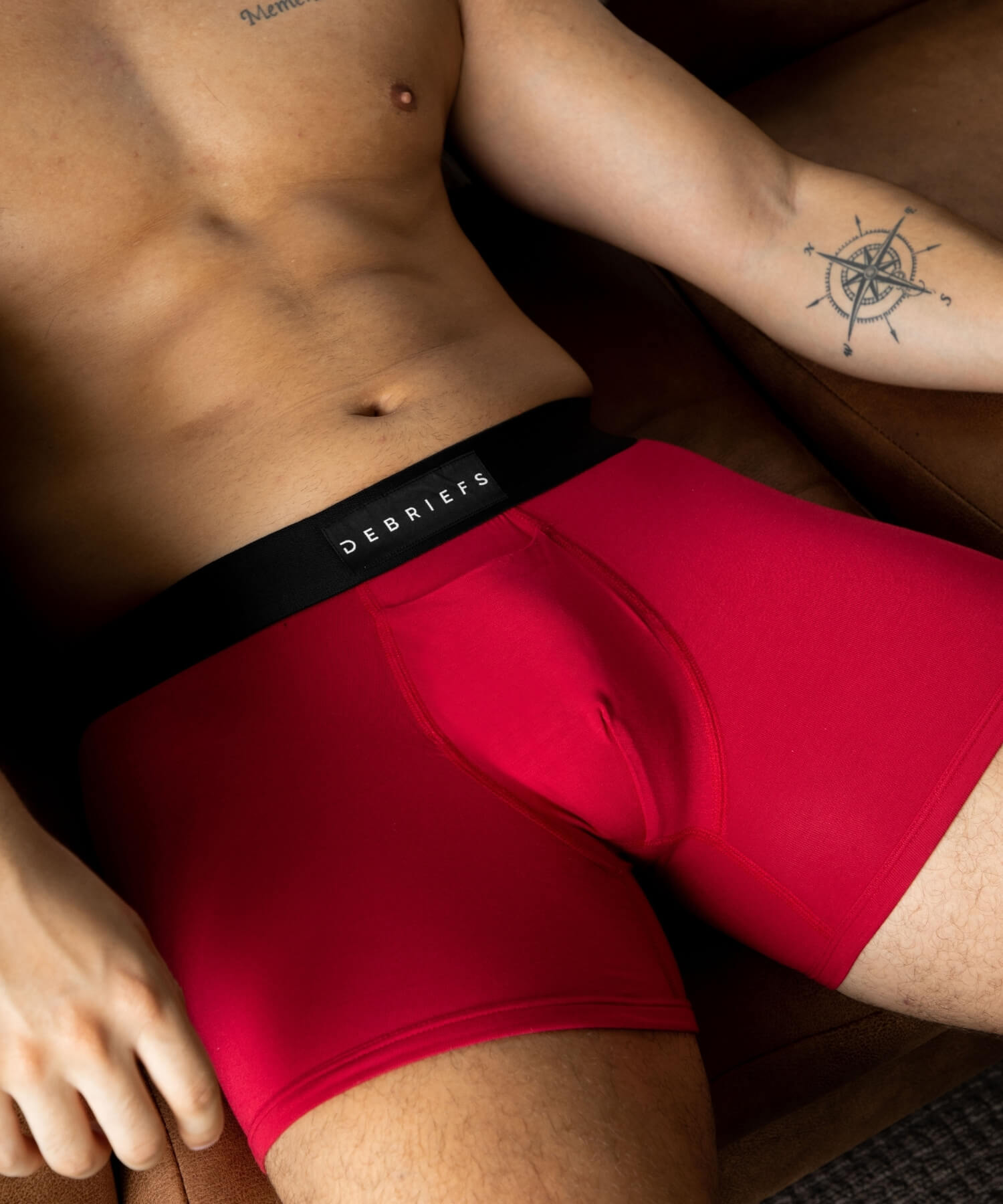 Man lying on couch wearing red Debriefs boxer briefs underwear