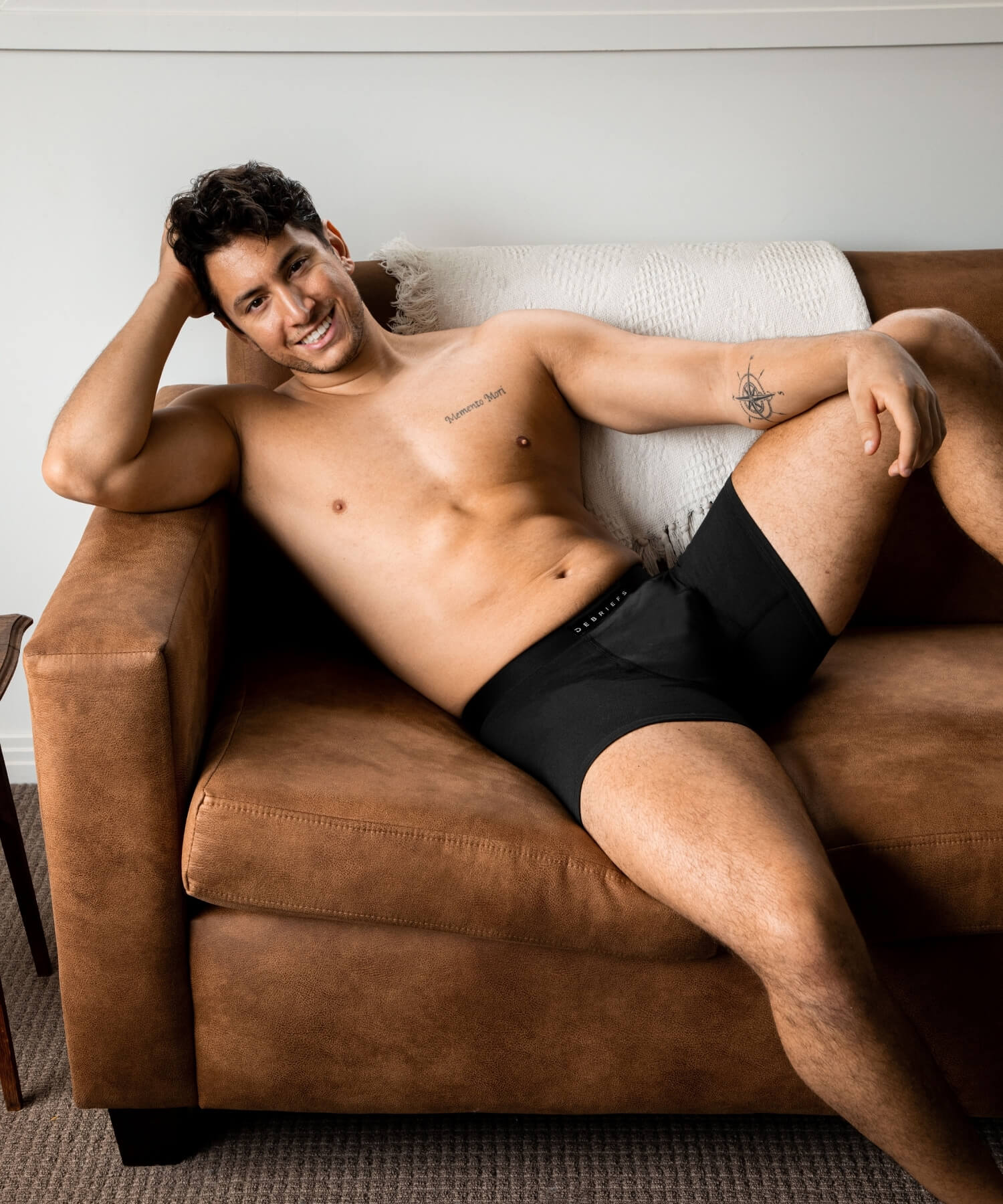 Man sitting on couch smiling wearing black Debriefs boxer briefs underwear